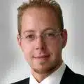 Eine Person in formeller Kleidung schaut freundlich in die Kamera.