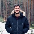 Eine Person in Winterjacke lächelt in einem verschneiten Wald, ideal für Imagevideos mit naturfreundlichem Kontext.