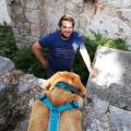 Person mit Hund in einer urbanen Umgebung bei Steinmauern, möglicherweise bei einem Film- oder Videodreh für eine Gemeindefilmproduktion.